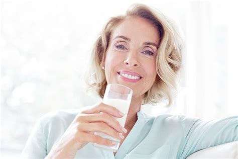 mature woman smiling with drink photograph by science photo library