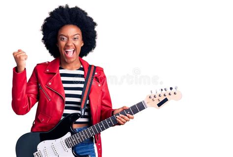 Young African American Woman Playing Electric Guitar Screaming Proud