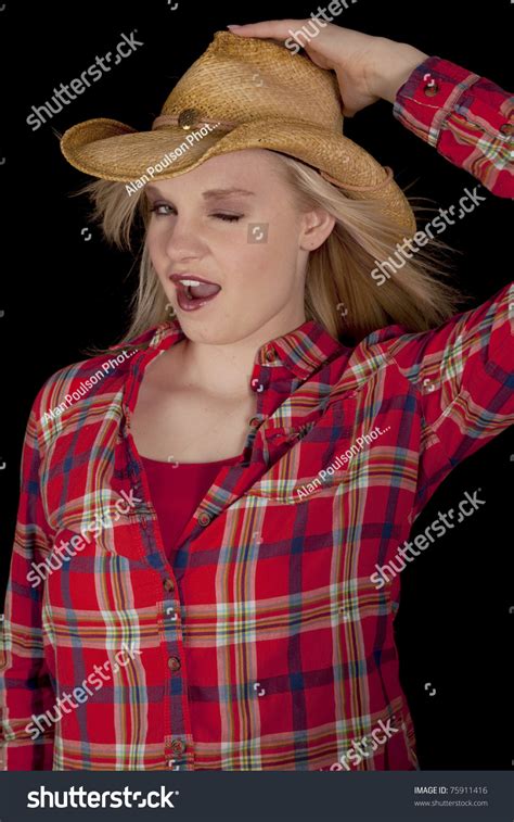 A Teen Cowgirl Hanging Onto Her Hat While The Wind Blows Giving A Wink