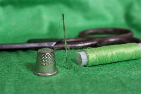 Spool Of Green Thread Thimble And Needle On Green Fabric Stock Photo