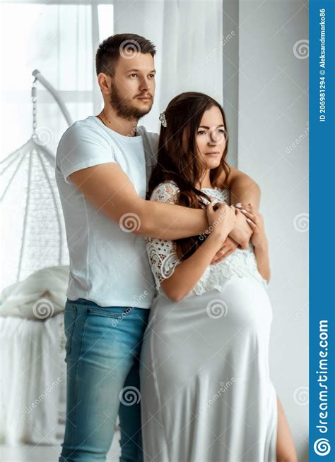 A Pregnant Girl With Her Husband Are Standing In A Bright Bedroom Beautiful Belly Of A Young