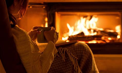 Young Woman Sitting At Home By The Fireplace And Reading A Book Stock