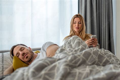 Suspicious Young Wife Checking Husbands Mobile Phone While Her Husband Sleeping Stock Foto