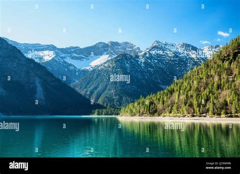 Turquoise Mountain Lake Surrounded By Green Forests And Snow Capped