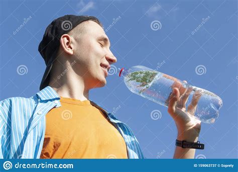 Hombre Tomando Agua De Una Botella Contra Un Cielo Azul Imagen De