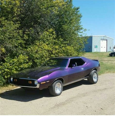 A Purple Muscle Car Parked On The Side Of A Dirt Road Next To Some Trees