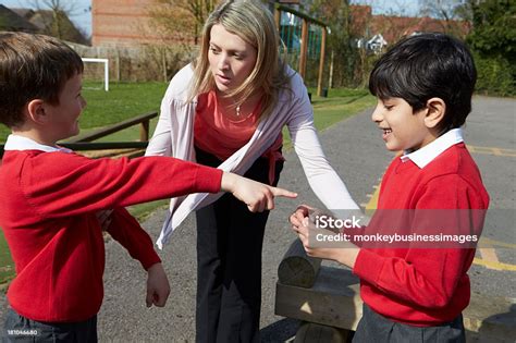 Teacher Stopping Two Boys Fighting In Playground Stock Photo Download
