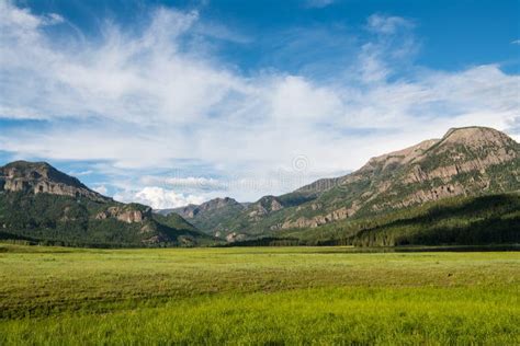 Grassy Meadow And Open Ranch Land Surrounded By High Mountain Peaks