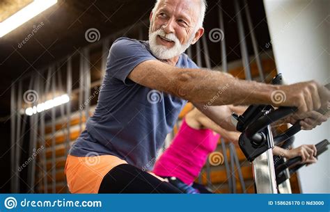 Happy Fit Mature Woman And Man Cycling On Exercise Bikes To Stay Healthy Stock Photo Image Of