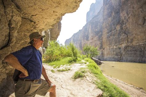 Senior Man Exploring Brown River In A Steep Walled Desert Canyon Stock