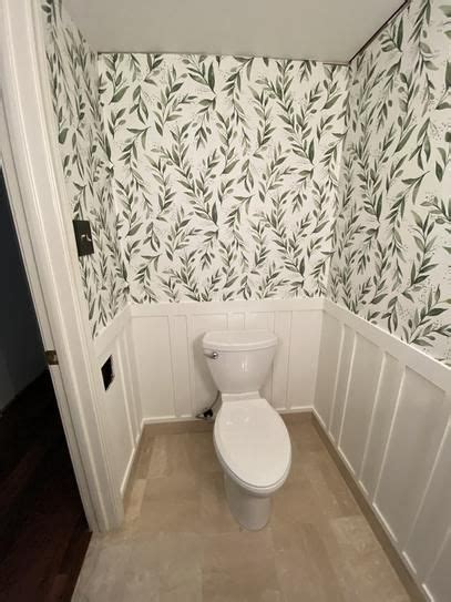 A White Toilet Sitting Inside Of A Bathroom Next To A Wall Papered With