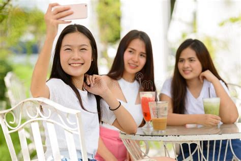 Three Happy Young Asian Women As Friends Taking Selfie Together At The Coffee Shop Outdoors