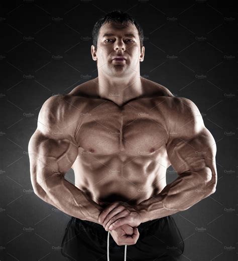 Handsome Muscular Bodybuilder Posing Over Black Background Featuring