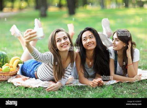 Cheerful Smiling Girls Taking Selfie Lying On Blanket On Grass Multi