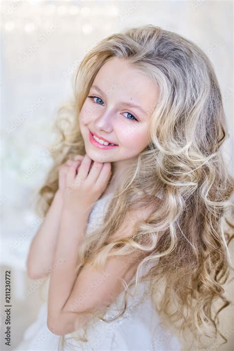Beautiful Little Girl With Long Blonde Hair Poses In The Studio Stock