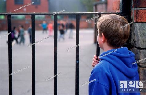 Young Boy Excluded From School Looking Through Metal Railings At