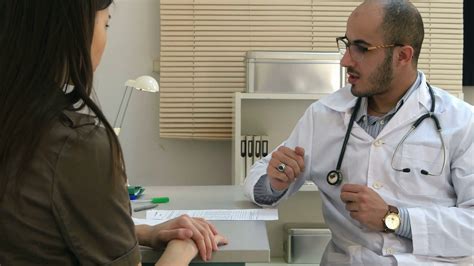 Male Doctor Prescribing Pills To Female Patient And Explaining Side