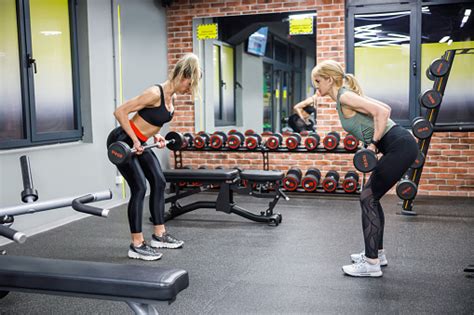 Women Working Out Together In The Gym Bending Over And Lifting Barbells