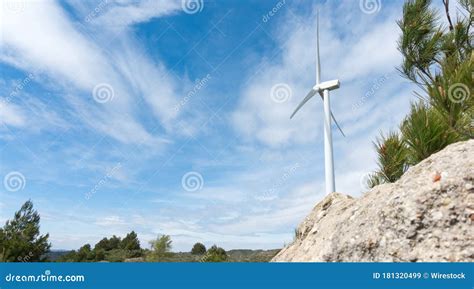 Panoramic Shot Of A Windmill Surrounded By Greenery And Rocks Under A