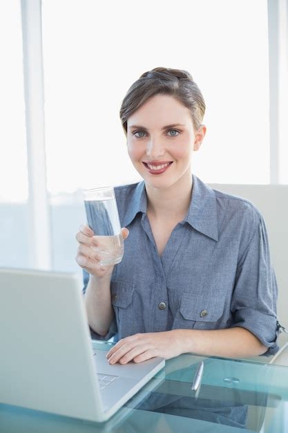 Premium Photo Beautiful Smiling Businesswoman Holding A Glass Of Water Sitting At Her Desk