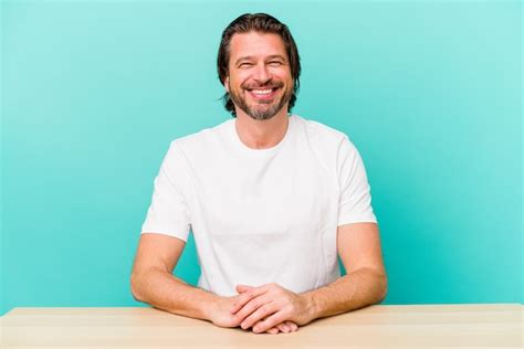 premium photo middle age dutch man sitting isolated on blue happy smiling and cheerful