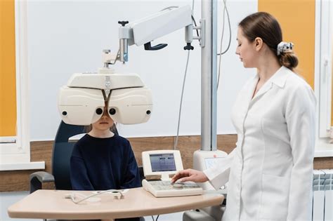 小児眼科医の眼科検査中にフォロプターを覗き込む子供 屈折異常を測定し、眼鏡の処方情報を決定するためのフォロプター プレミアム写真