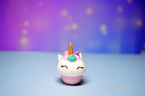 A Small Toy Cupcake With A Unicorn Horn On Its Head Sitting On A Blue