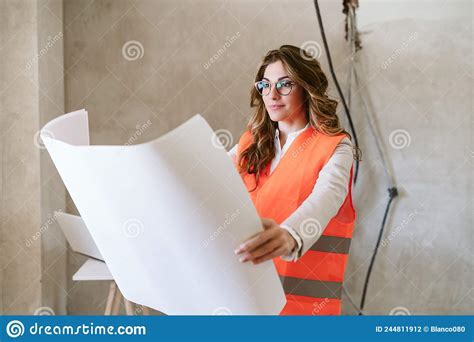 professional confident architect woman in construction site holding blueprints home renovation