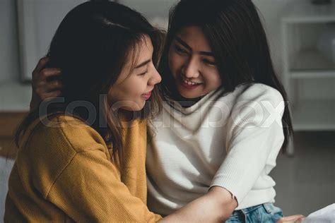 asian lesbian lgbt couple hug and sitting on bed near white window sunlight with happiness