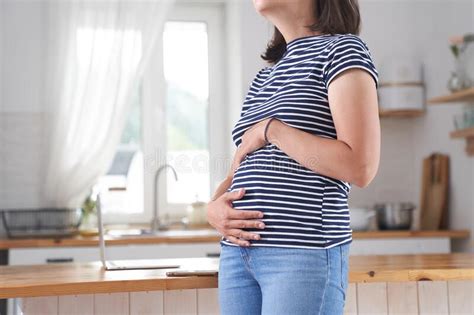 A Young Pregnant Woman Holds Her Stomach With Her Hands A Brunette