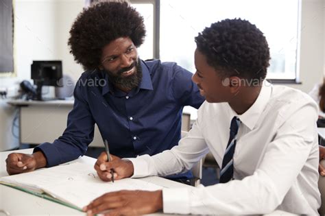 High School Tutor Giving Uniformed Male Student One To One Tuition At