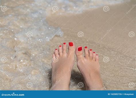 Woman Legs With Pedicure Laying On Beach With The Waves And White Sand
