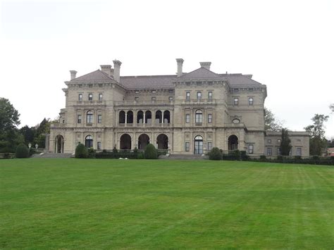 A Large Building With Lots Of Windows On Top Of A Lush Green Field