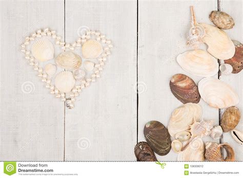 Group Of Sea Shells And Pearls Laid Out In The Shape Of Heart On White