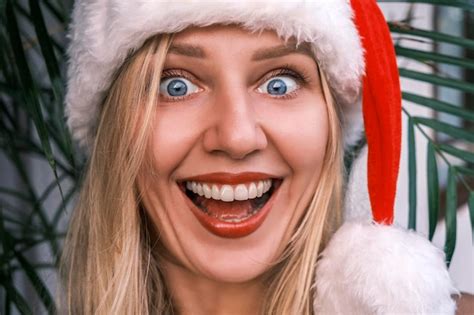 Premium Photo Funny Broadsmiling Blonde Woman Wearing Santa Hat Looking Into Camera With