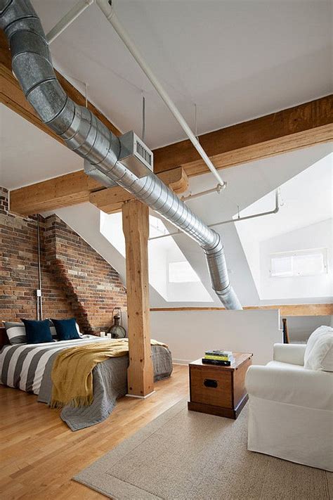 A Loft Bedroom With Exposed Brick Walls And White Furniture Along With