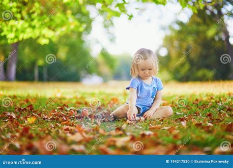 Unhappy And Emotional Toddler Girl Sitting On The Ground In Park Stock