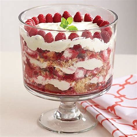 a trifle with strawberries and cream in a glass dish on a white table