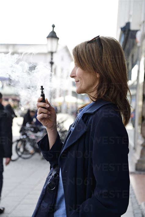 Mature Woman Smoking Electronic Cigarette In The City Stock Photo