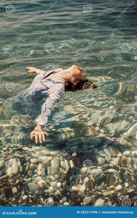 A Girl In A Denim Jumpsuit Stands Breast Deep In Seawater Her Body Is