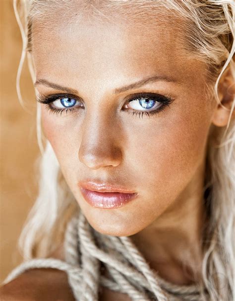 A Beautiful Blond Woman With Blue Eyes And Braids On Her Neck Looking At The Camera