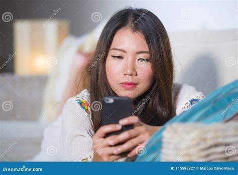 Young Beautiful And Happy Asian Chinese Woman On Her 20s Or 30s Lying At Living Room Sofa Couch