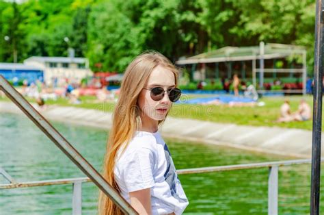 Summer Portrait Of A Blonde Girl In Glasses On A Lake Background Stock