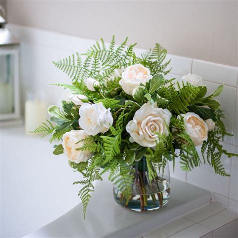 A Vase Filled With White And Pink Flowers On Top Of A Counter Next To A