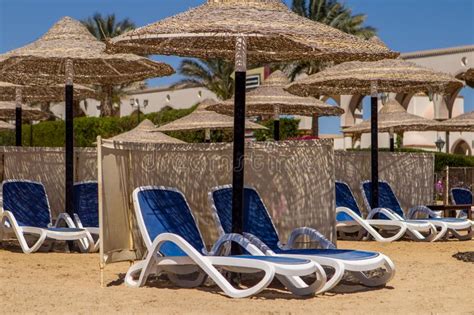 Two Sun Loungers Under An Umbrella On The Sandy Beach View From The