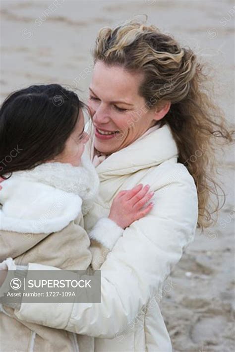 Mid Adult Woman Hugging Her Daughter On The Beach Superstock