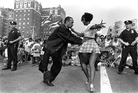 A Man And Woman Dancing On The Street In Front Of A Group Of Police