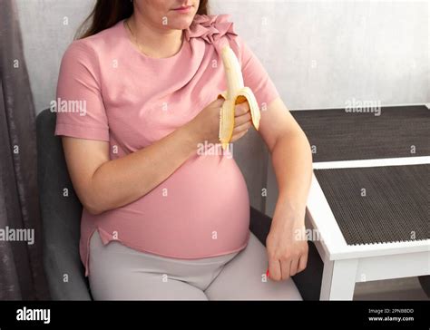 A Pregnant Girl Eats A Banana In The Kitchen The Concept Of Healthy