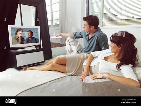 Happy young couple watching television together at home Stock Photo ...