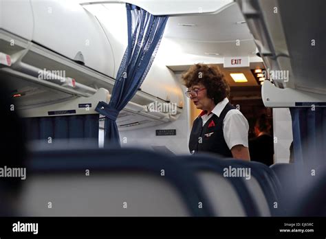 female flight attendant in airplane aisle talks to passenger during flight on airplane stock